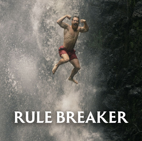 Man in red shorts jumping from a waterfall with 'Rule Breaker' text below.